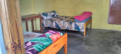 a room with two beds and a bench in it at N L Homestay in Cherrapunji