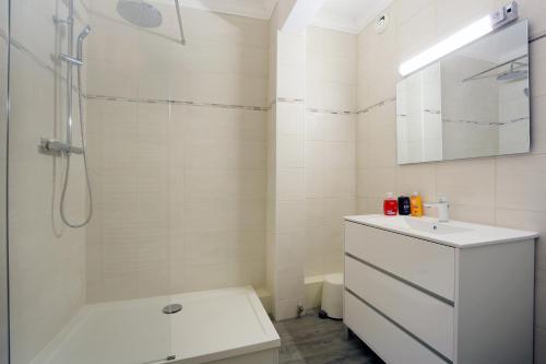 une salle de bain blanche avec une douche et un lavabo dans l'établissement Le jaune Place Saint Georges 100m Parking Terrasse, à Toulouse