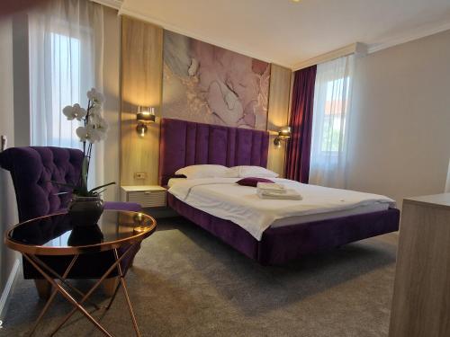 um quarto com uma cama roxa e uma mesa em Hotel Casa David em Craiova
