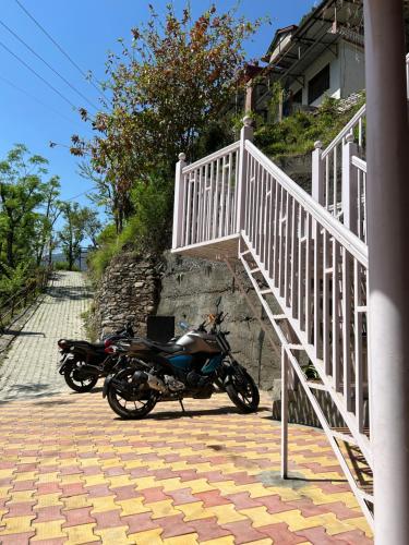 a motorcycle parked next to a white stair case at Lemonade Inn in Chamba