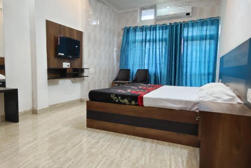 um quarto com uma cama com 2 cadeiras e uma televisão em Goroomgo Hotel The Nirmala Palace Ayodhya-Near Ram Mandir em Ayodhya