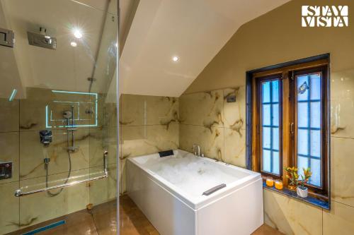 a bathroom with a bath tub and a shower at StayVista at Swiss Chalet - Tangmarg with Gazebo & Lawn in Tangmarg