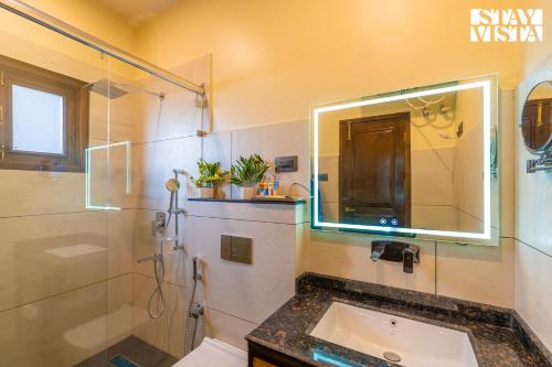 a bathroom with a sink and a shower and a mirror at StayVista at Swiss Chalet - Tangmarg with Gazebo & Lawn in Tangmarg