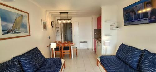 sala de estar con 2 sillas azules y cocina en Agay Cap Esterel, le village Belvédère T2 climatisé Rez-de-Jardin, Vue Mer, Piscine et Parking inclus, en Agay - Saint Raphael