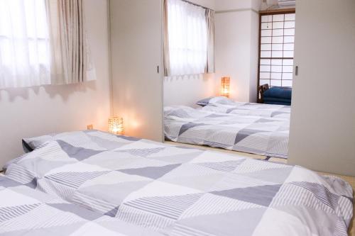 two white beds in a room with a mirror at 名古屋の部屋駅近で人工温泉のお風呂が楽しめます in Yadachō