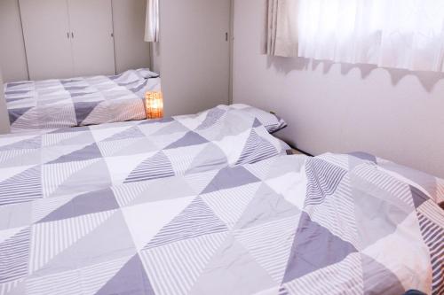 two beds in a bedroom with a quilt at 大曽根駅から徒歩5分人工温泉が24時間楽しめてナゴヤドームまで徒歩で行く事が出来ます in Yadachō