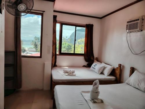 Cette chambre comprend 2 lits et une fenêtre. dans l'établissement Brenmariel Tourist Inn, à El Nido