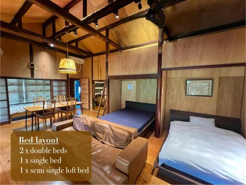 熊本市にあるSUMITSUGU HOUSE Westのベッド2台付きの部屋、テーブル付きのダイニングルームが備わります。