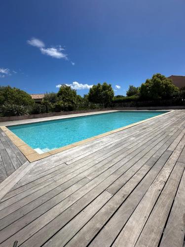 une grande piscine avec une terrasse en bois dans l'établissement Porto vecchio Résidence Don Andria T2, à Lecci