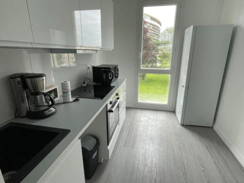 uma cozinha com armários brancos e um frigorífico branco em Appartement champs de course, proche paris centre em Eaubonne