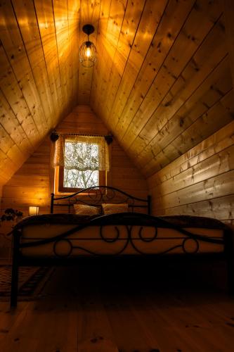 a bedroom with a bed in a attic with a window at Chata Czarny Kot z jacuzzi i sauną in Janowice Wielkie