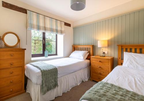 a bedroom with two beds and a window at Bwthyn Gwyn in Llanerchymedd