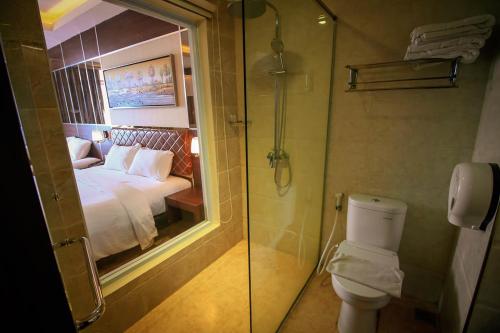 a bathroom with a shower and a toilet and a bed at Batam City Hotel in Nagoya