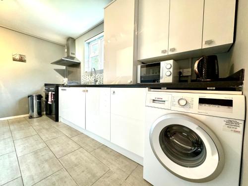 a kitchen with a washing machine in a kitchen at The Standalone - 4 Bedroom Home with Garden by Wild in London