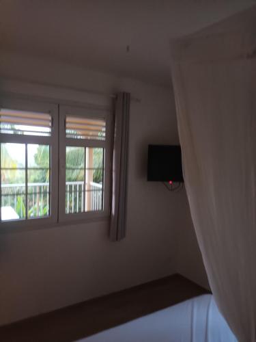 1 Schlafzimmer mit 2 Fenstern und einem TV in der Unterkunft Martinique La petite maison dans la Colline in Le Lamentin
