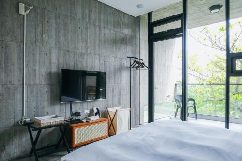 a bedroom with a tv on a concrete wall at 樹墅Villa宜蘭寵物友善包棟民宿丨溜滑梯丨烤肉丨Switch in Ch'eng-hsing