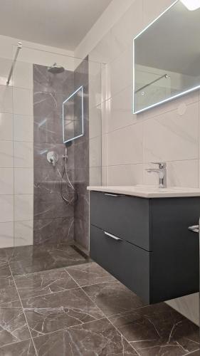 a bathroom with a sink and a shower with a mirror at Santima Apartments in Baška