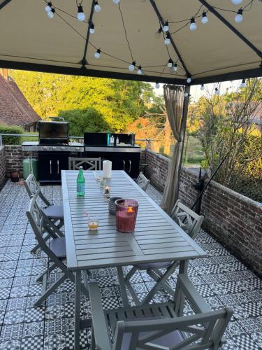 einen Picknicktisch unter einem Sonnenschirm auf einer Terrasse in der Unterkunft Maison Normandie 