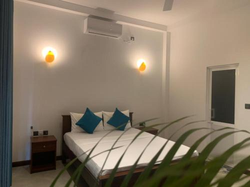 Un dormitorio con una cama con almohadas azules y una ventana en Oqura Villa, en Ahangama