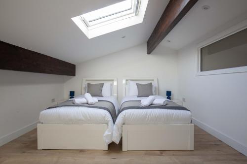 two beds in a room with white walls at York Cottage in Cirencester
