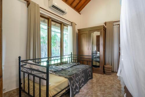 a bedroom with a bed and a large window at Buntung Beach Villa in Gili Air