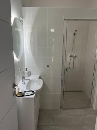 a white bathroom with a shower and a sink at Shubu GARDEN Vendégházak in Szilvásvárad