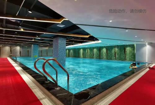 a large swimming pool in a building with a red carpet at Mercure Shenzhen Nanshan in Shenzhen