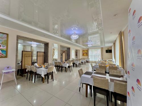 een eetkamer met tafels en stoelen in een restaurant bij Raduga West 'Azure' Apartment in Koshkolʼ