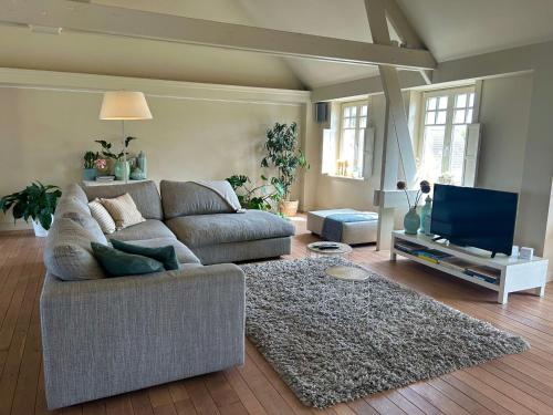 The Loft في Melsele: غرفة معيشة مع أريكة وتلفزيون بشاشة مسطحة