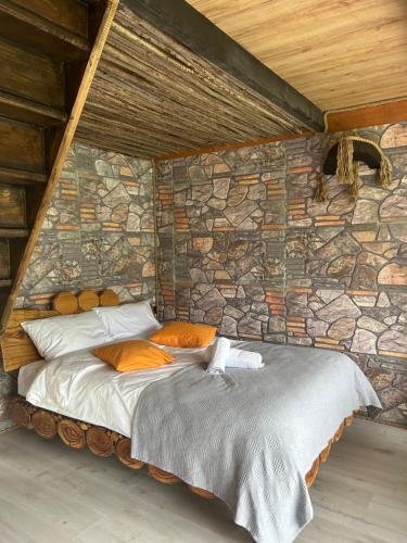 a bed in a room with a stone wall at FİÇİTA BUNGALOv in Dikkaya