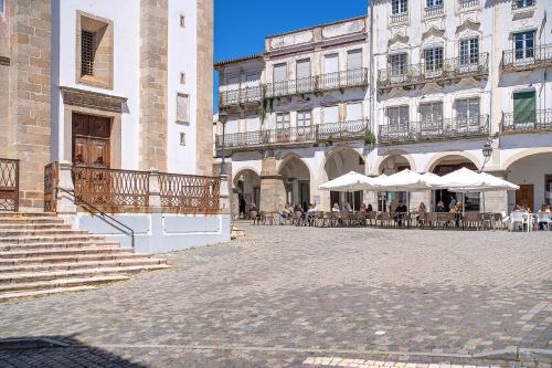 a courtyard of a building with tables and umbrellas at Bright House Évora in Évora
