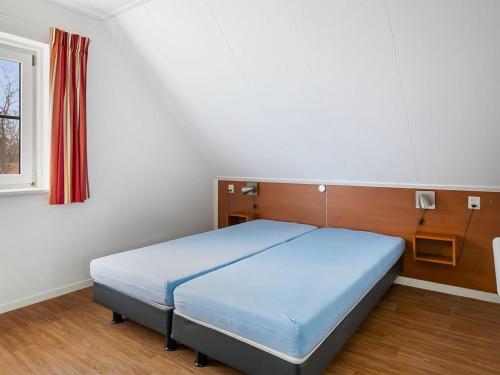 1 dormitorio con 1 cama azul en una habitación con ventana en Holiday home with conservatory, near Hellendoorn, en Hellendoorn