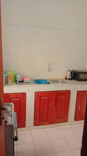 a kitchen with red cabinets and a sink at BG archange in Cotonou