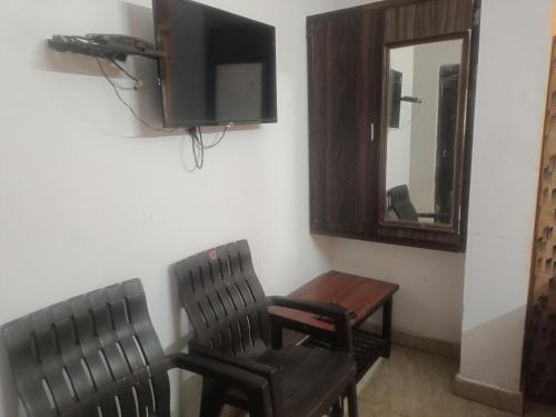 een kamer met 2 stoelen, een tafel en een tv bij Sapthagiri lodge in Visakhapatnam