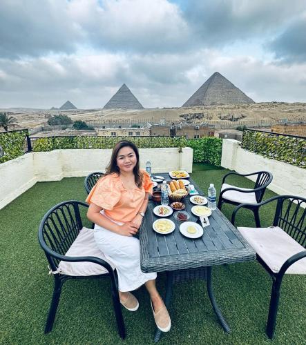 a woman sitting at a table in front of pyramids at Solima pyramids in Cairo