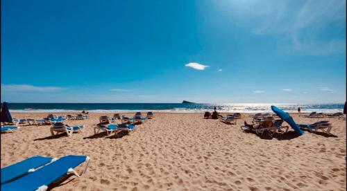 a beach with chairs and people on the sand at Apartamento las OLAS playa de levante in Benidorm