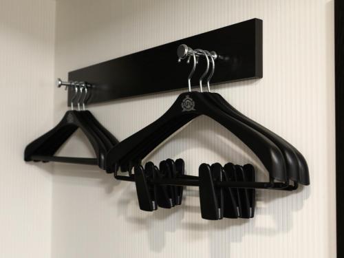 a black rack with three black hangers on a wall at APA Hotel Sapporo Susukino Ekimae in Sapporo