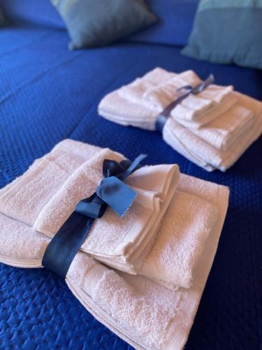 two towels with a blue tie on a bed at Casa Nando Relax e comfort home in Marina di Ascea