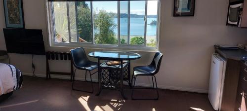 um quarto com uma mesa e duas cadeiras e uma janela em Top of the Bay em Paihia