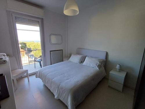 a white bedroom with a bed and a window at Appartamento vista mare Misano Adriatico in Misano Adriatico