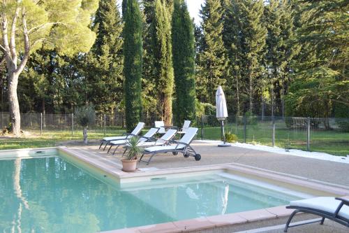 - une piscine avec 4 chaises et un parasol dans l'établissement Le Domaine d'Euphony, à Monteux
