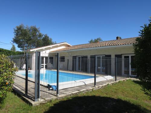 einen Zaun um einen Pool neben einem Haus in der Unterkunft Maison spacieuse avec piscine sur le Bassin d'Arcachon in Lanton