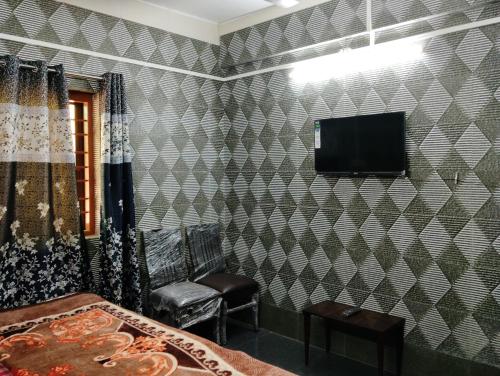 1 dormitorio con pared de azulejos, TV y sillas en ROGHAY COTTAGE en Mātherān