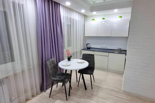 - une cuisine avec une table et des chaises blanches dans la chambre dans l'établissement Coffee Boom, à Kökşetaw