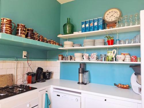 a kitchen with shelves with dishes and a clock at Cœur Toulouse Piscine et Spa in Toulouse