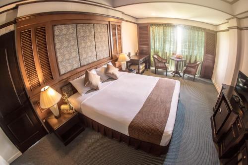 a hotel room with a large bed and a desk at Lampang Wieangthong in Lampang