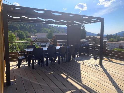 a patio with a table and chairs on a deck at Le joli bois 12 personnes 5/ch spa/sauna Gérardmer in Gérardmer