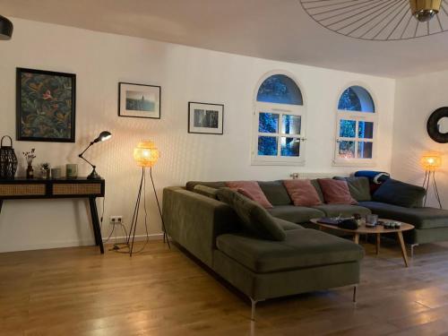 ein Wohnzimmer mit einem Sofa, einem Tisch und 2 Fenstern in der Unterkunft Maison située à Montmorency (95) disponible pour les JO in Montmorency