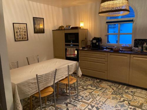 eine Küche mit einem Tisch, Stühlen und einer Theke in der Unterkunft Maison située à Montmorency (95) disponible pour les JO in Montmorency