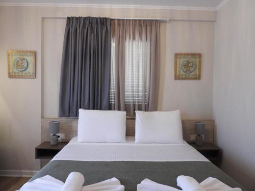 a bedroom with a bed with white pillows and a window at Saint george Hotel Parga in Parga